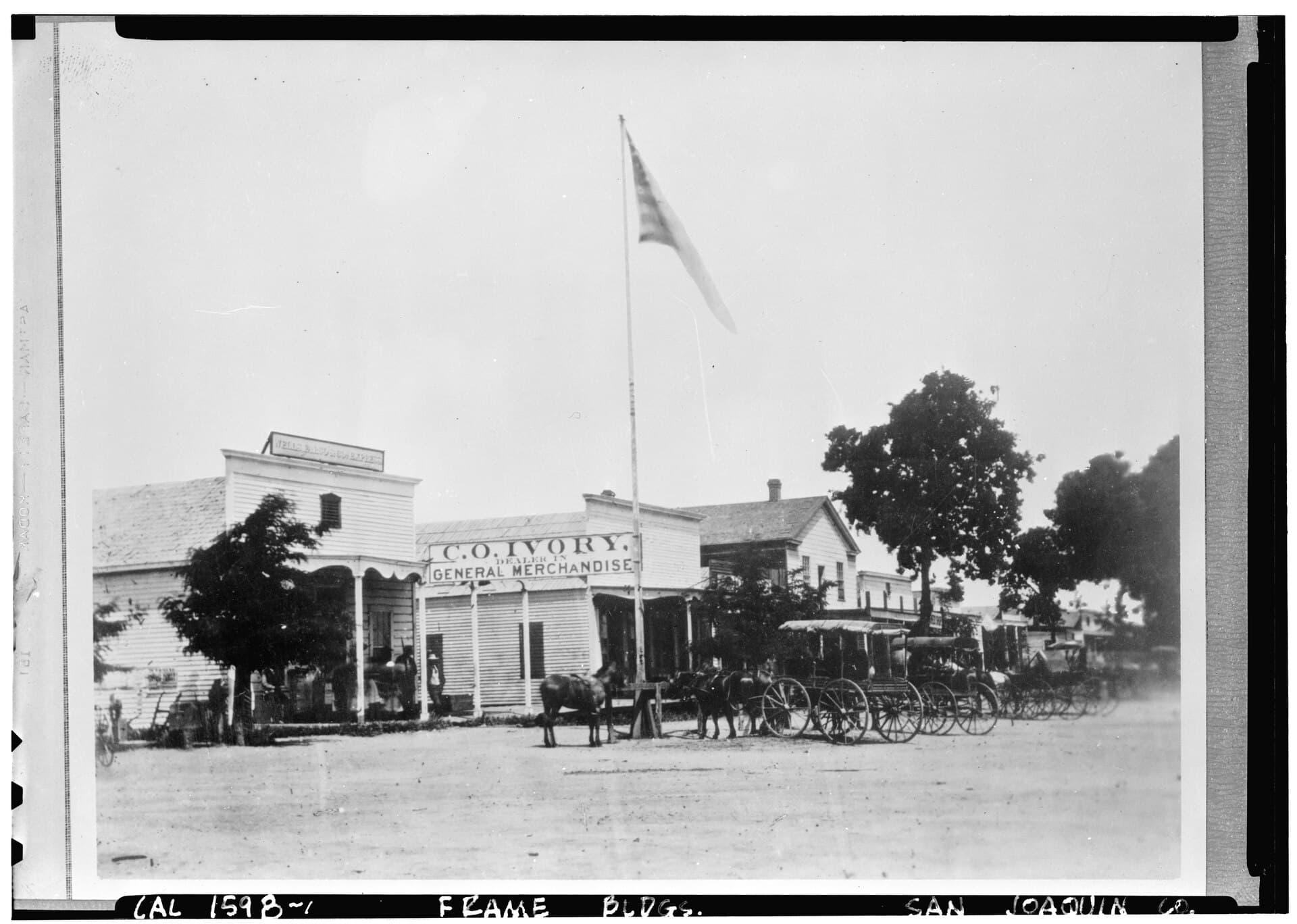 Historic black-and-white street view of commercial buildings in Lodi with awnings, wagons, and pedestrians.