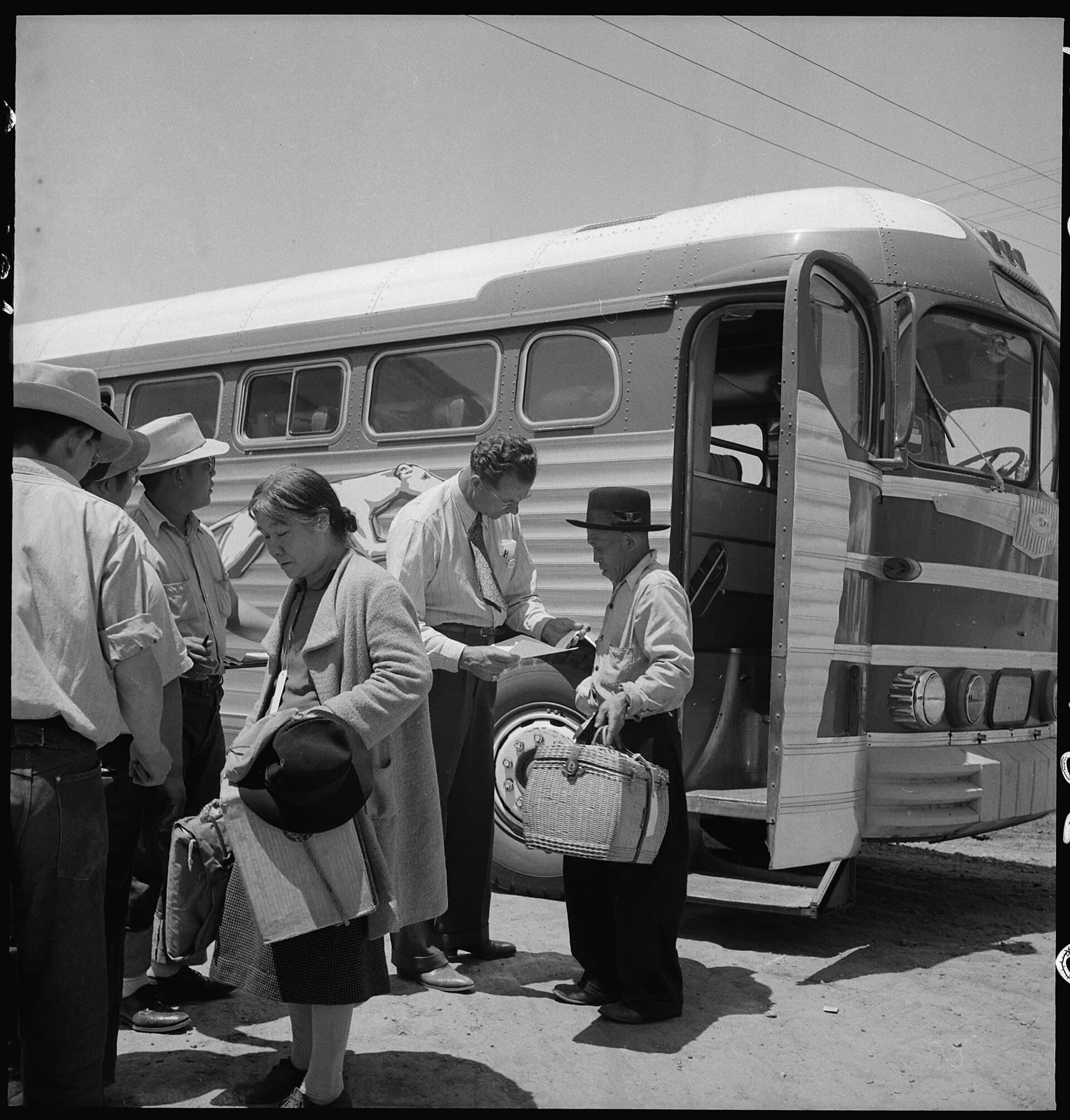 Japanese American families from the Lodi grape-growing district wait with baggage beside a bus in Stockton in 1942.
